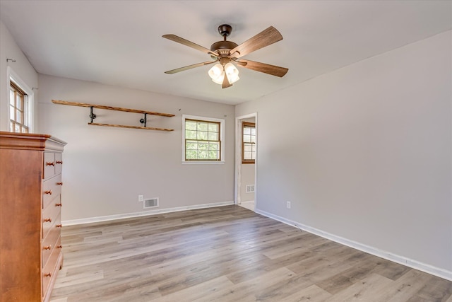 empty room featuring a ceiling fan, light wood-type flooring, and baseboards