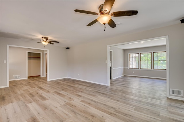 empty room featuring a ceiling fan, light wood-style flooring, and baseboards