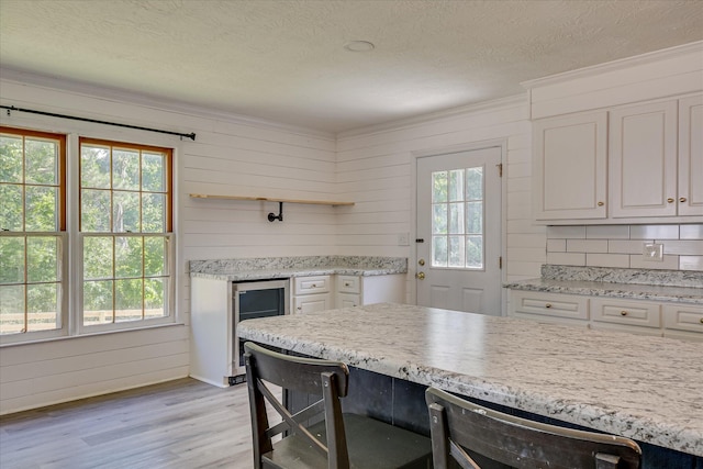 kitchen with open shelves, light wood-type flooring, crown molding, beverage cooler, and white cabinets