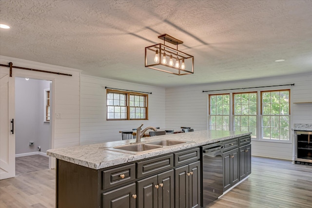 kitchen with dishwasher, a textured ceiling, a sink, wine cooler, and light wood finished floors