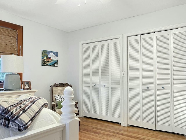 bedroom featuring multiple closets, ceiling fan, and light hardwood / wood-style floors