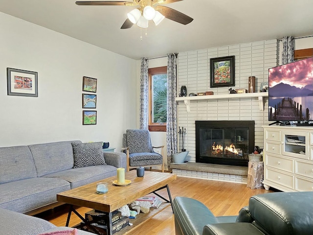 living room with a brick fireplace, hardwood / wood-style floors, and ceiling fan