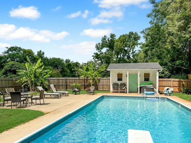 view of pool featuring an outbuilding, a diving board, and a patio area