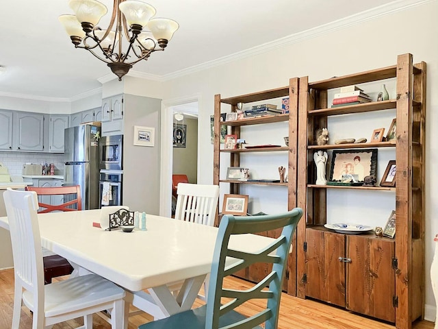 dining area featuring ornamental molding, a notable chandelier, and light hardwood / wood-style flooring