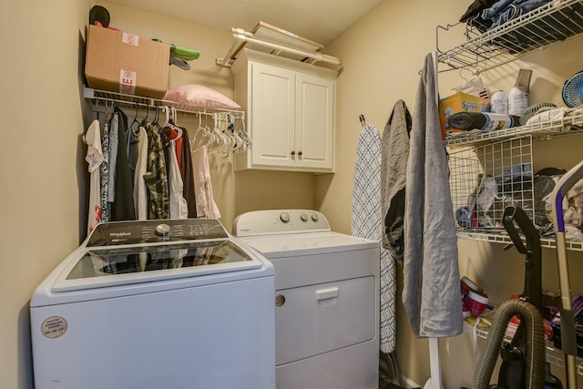 clothes washing area with separate washer and dryer and cabinet space