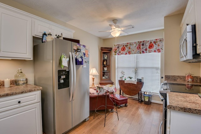 kitchen with light wood finished floors, stainless steel appliances, a ceiling fan, white cabinets, and a textured ceiling