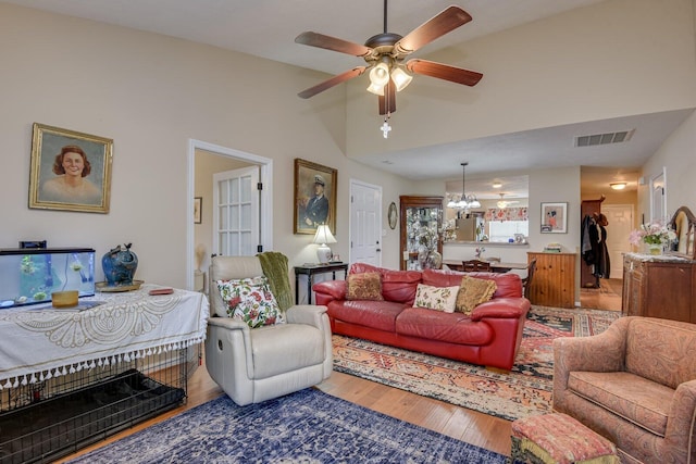 living room with vaulted ceiling, ceiling fan with notable chandelier, wood finished floors, and visible vents