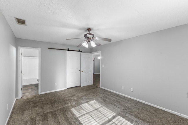 26 Charlestowne Dr, Augusta, GA 30907 - unfurnished bedroom with carpet flooring, baseboards, a barn door, a closet, and a ceiling fan