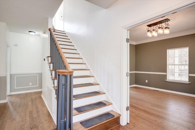 staircase with crown molding and wood-type flooring