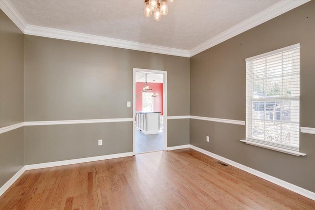 empty room with hardwood / wood-style floors, an inviting chandelier, and plenty of natural light