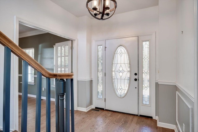 entrance foyer featuring hardwood / wood-style floors, crown molding, and a notable chandelier