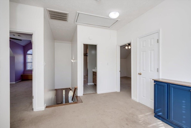 corridor featuring a textured ceiling and light colored carpet