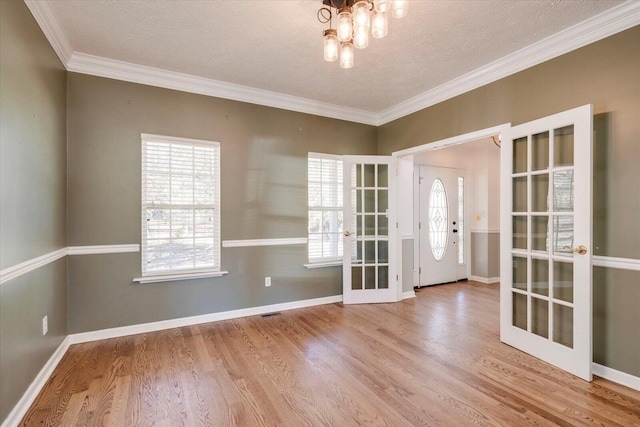 interior space with french doors, a textured ceiling, light hardwood / wood-style flooring, and crown molding