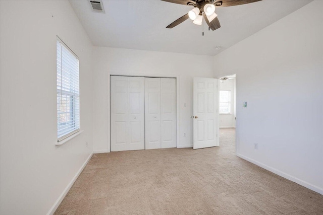 unfurnished bedroom featuring ceiling fan, light carpet, and a closet