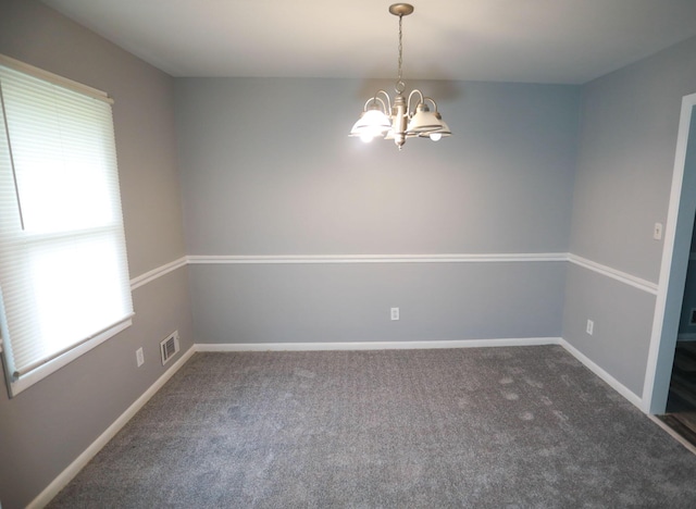 empty room featuring dark carpet and a notable chandelier