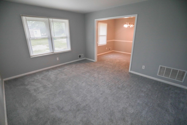 empty room featuring dark colored carpet and an inviting chandelier