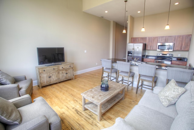 living room featuring a high ceiling, light hardwood / wood-style flooring, and sink