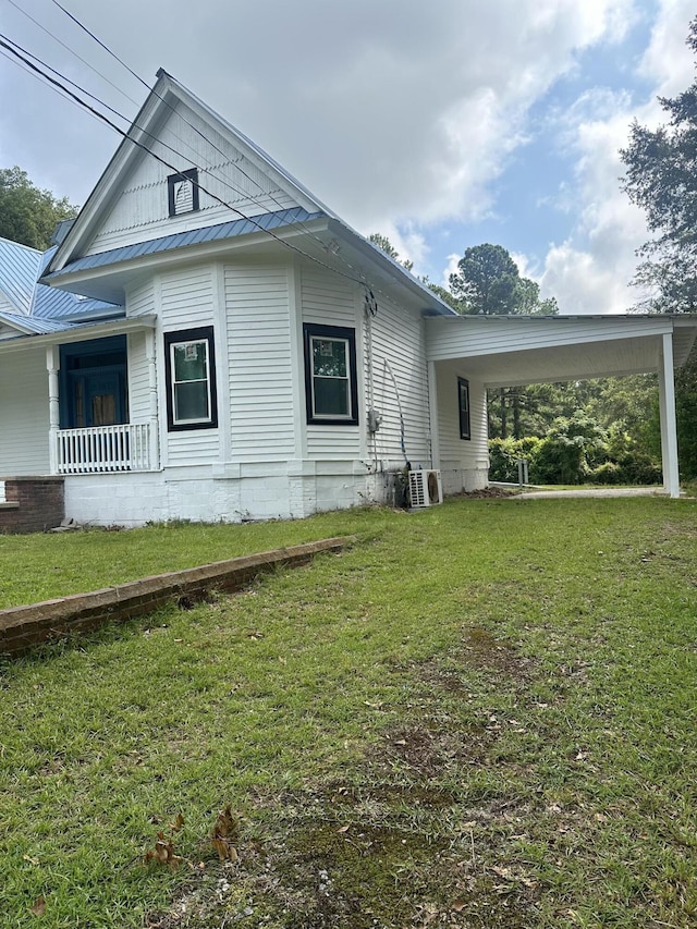 view of side of property with a carport and a lawn