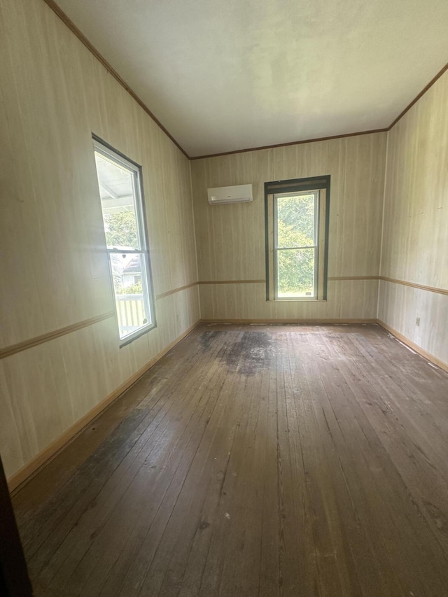 empty room with an AC wall unit and hardwood / wood-style flooring