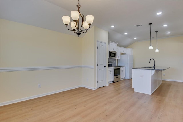 kitchen with appliances with stainless steel finishes, a kitchen island with sink, hanging light fixtures, dark stone countertops, and white cabinets