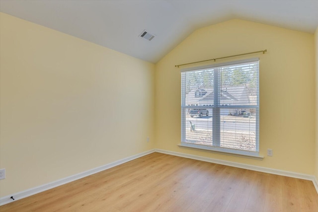 empty room featuring light hardwood / wood-style flooring, plenty of natural light, and vaulted ceiling