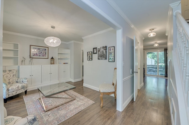 hall featuring built in features, wood finished floors, crown molding, baseboards, and a chandelier