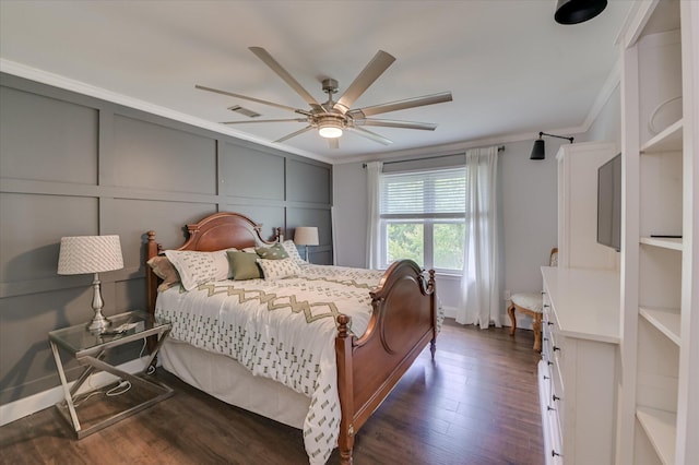 bedroom featuring ornamental molding, dark wood-type flooring, a ceiling fan, and a decorative wall