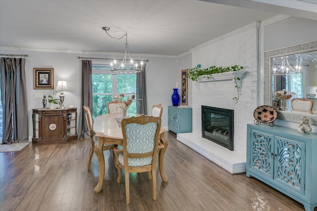 dining area featuring a chandelier, wood finished floors, ornamental molding, and a brick fireplace