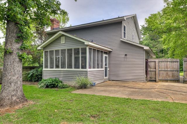 back of property featuring a sunroom, a chimney, and a patio