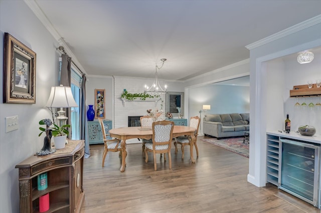 dining area with wine cooler, a chandelier, wood finished floors, a bar, and crown molding
