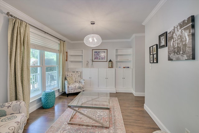 sitting room featuring built in shelves, crown molding, dark wood-style floors, baseboards, and a chandelier