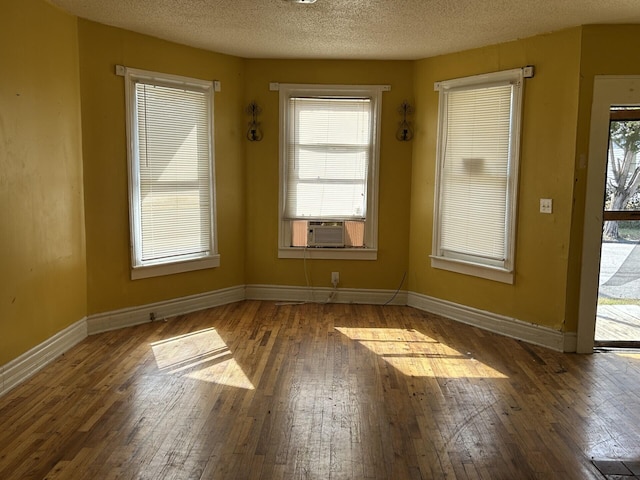 unfurnished room featuring cooling unit, dark hardwood / wood-style floors, and a textured ceiling