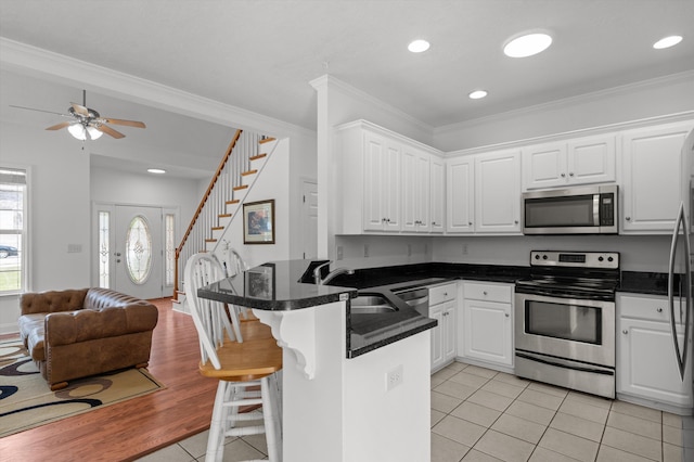 2532 Grier Cir, Evans, GA 30809 - kitchen with stainless steel appliances, a peninsula, a sink, white cabinets, and crown molding