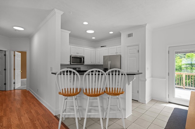 2532 Grier Cir, Evans, GA 30809 - kitchen with stainless steel appliances, a peninsula, white cabinetry, a kitchen bar, and crown molding
