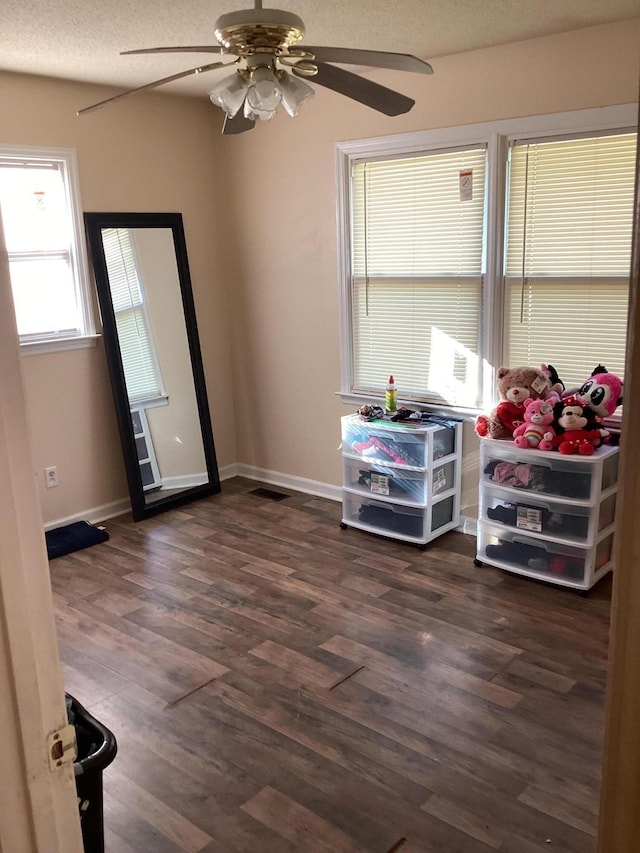 interior space featuring a textured ceiling, ceiling fan, and dark wood-type flooring