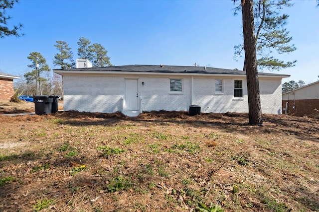 back of house with central AC and brick siding