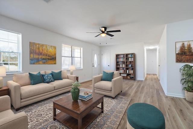 living room with light wood-type flooring, baseboards, and a wealth of natural light