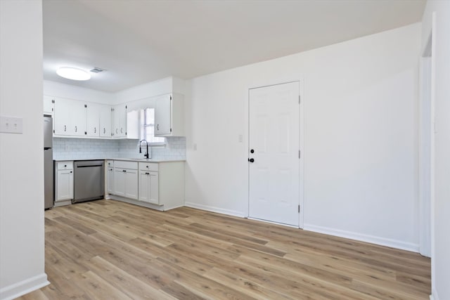 kitchen featuring light wood finished floors, stainless steel appliances, tasteful backsplash, light countertops, and white cabinetry