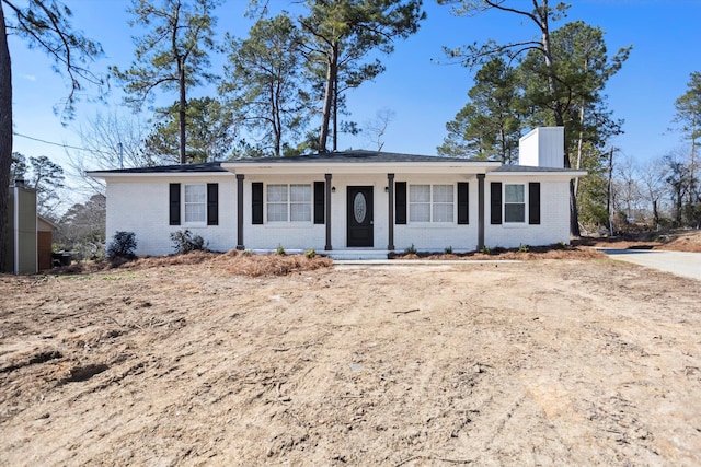 single story home with a chimney and brick siding