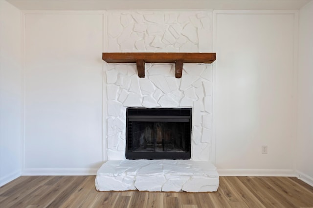 room details with a stone fireplace, wood finished floors, and baseboards