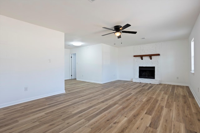 unfurnished living room with light wood-type flooring, a fireplace, baseboards, and a ceiling fan