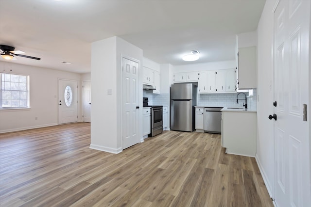 kitchen featuring under cabinet range hood, stainless steel appliances, a sink, white cabinets, and light countertops