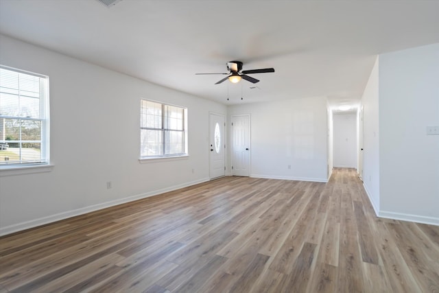 spare room featuring a ceiling fan, light wood-type flooring, a healthy amount of sunlight, and baseboards