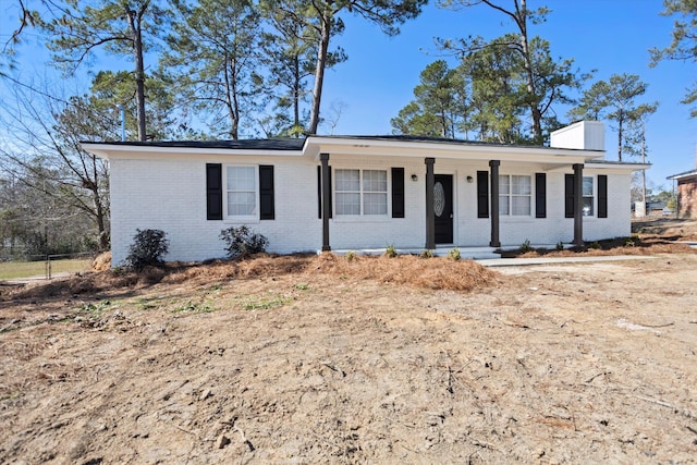 single story home featuring covered porch, brick siding, and a chimney