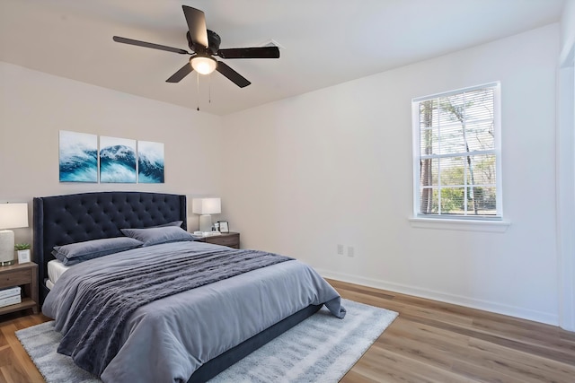 bedroom with ceiling fan, wood finished floors, and baseboards