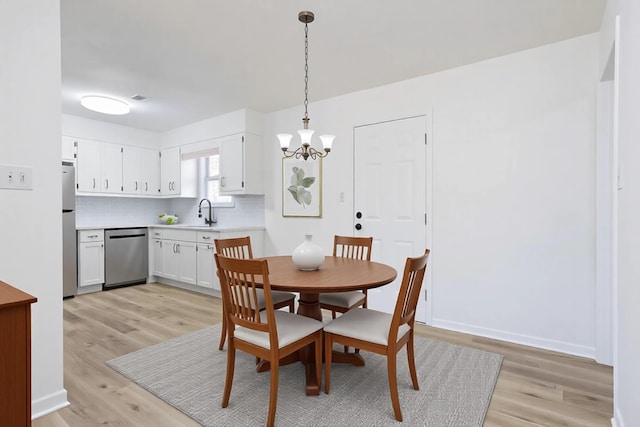 dining room featuring a chandelier, light wood-type flooring, visible vents, and baseboards