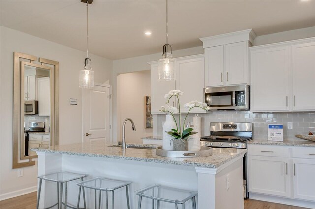 188 Scruple Way, North Augusta, SC 29860 - kitchen featuring a kitchen island with sink, tasteful backsplash, light stone counters, stainless steel appliances, and white cabinetry