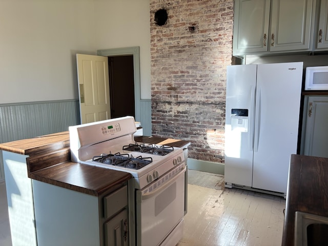 kitchen with gray cabinetry, white appliances, light hardwood / wood-style flooring, butcher block countertops, and brick wall