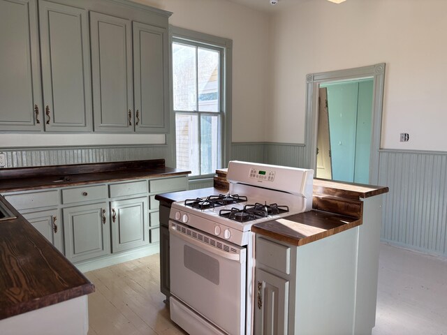 kitchen with wooden counters, light wood-type flooring, and white gas range oven