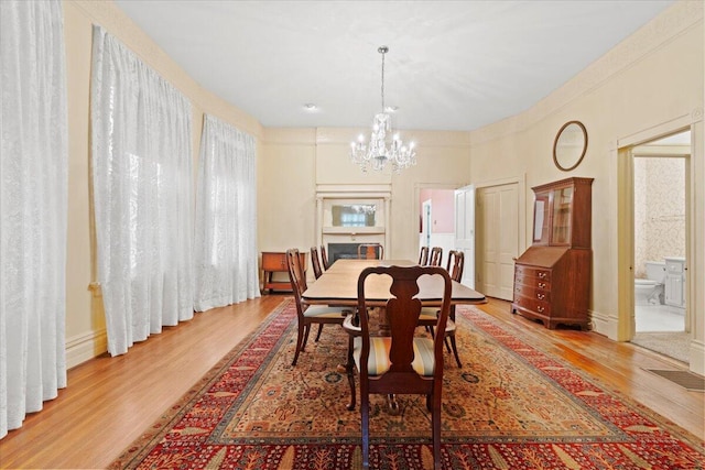 dining space with light wood-type flooring and a notable chandelier